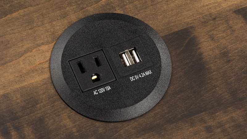 Round power hub built into furniture with 1 AC outlet ans 2 USB ports.